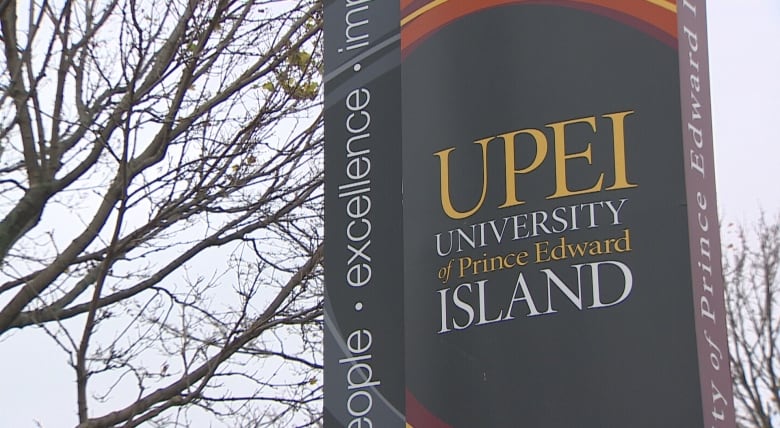 With a backdrop of bare tree branches, a large sign reads UPEI: University of Prince Edward Island.