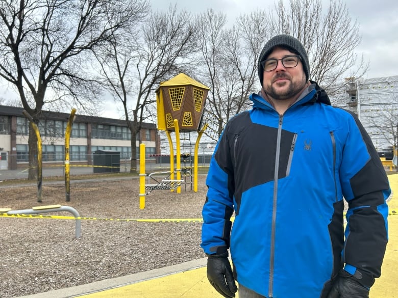 A man standing in front of a playground that is surrounded by police tape.