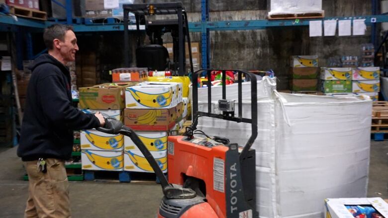 A man navigates a pallet through a warehouse.