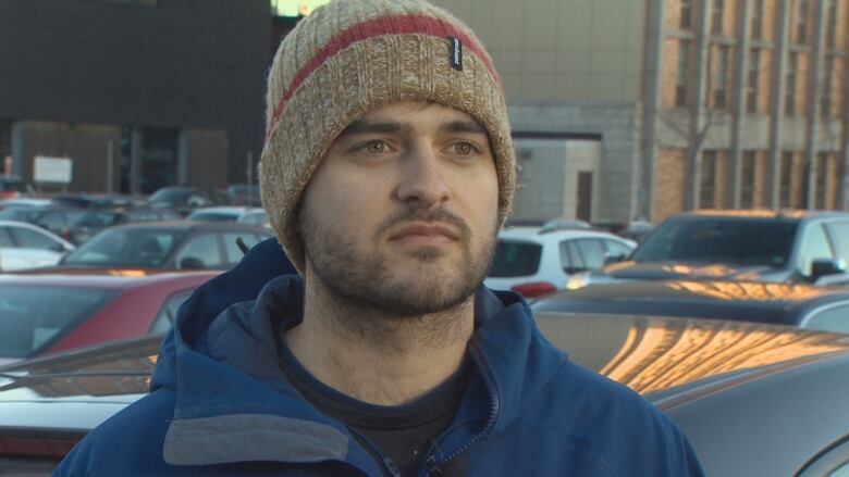 Drew Hubley stands in front of his car in a parking lot in downtown Halifax. 