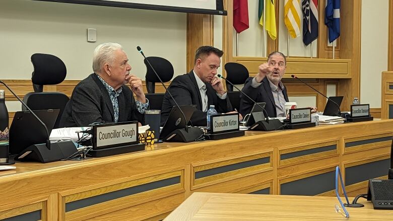 Councillors sit with greenlit microphones in front of them