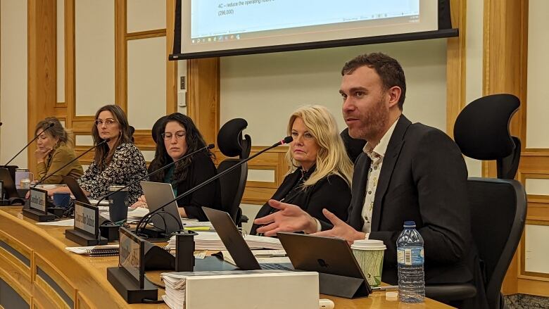 councillors sit at wooden desk with laptops in front of them