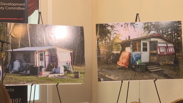 Two large pictures of beat-up houses in need of repair on easels. 