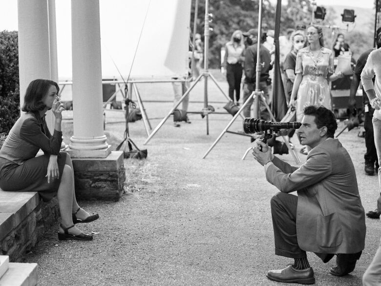 Director Bradley Cooper in costume as  Leonard Bernstein frames a shot with  Carey Mulligan as Felicia Montealegre in Maestro. 