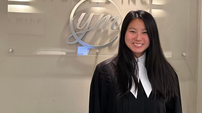 A woman in a black robe stands.