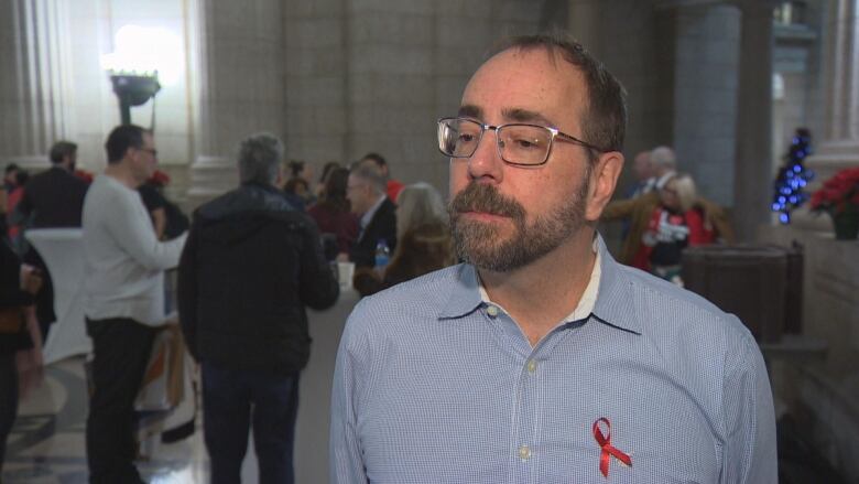 A man with short hair, a beard and glasses speaks to a reporter.