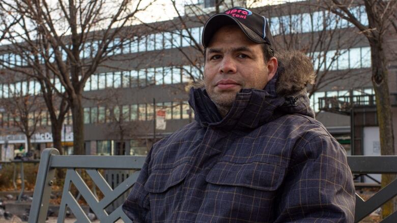 A man sits on a bench outside.