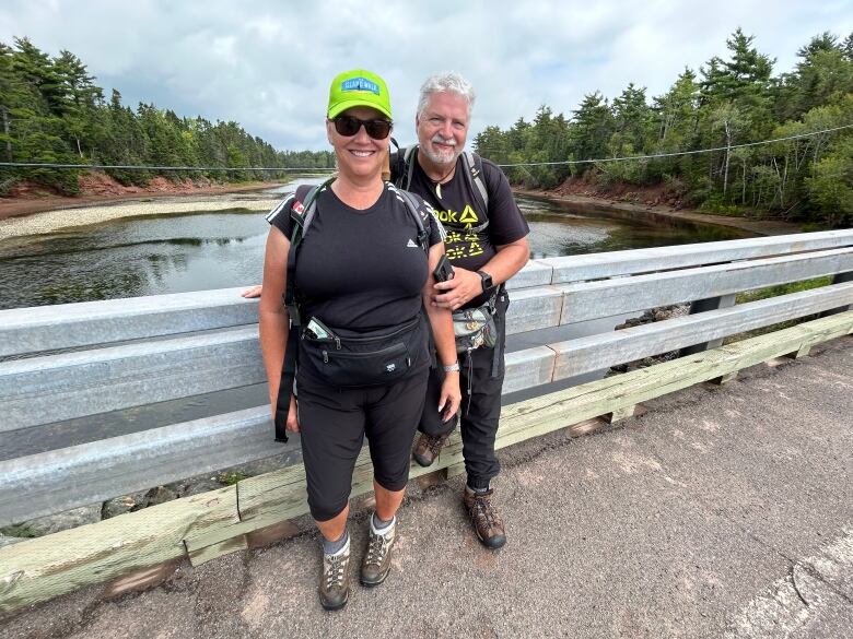 A man and woman wearing black with backpacks stop for a picture during the Island Walk  a 700 kilometre walk around Prince Edward Island.