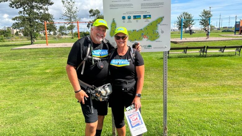 A man and woman wearing black with backpacks stop for a picture during the Island Walk  a 700 kilometre walk around Prince Edward Island.