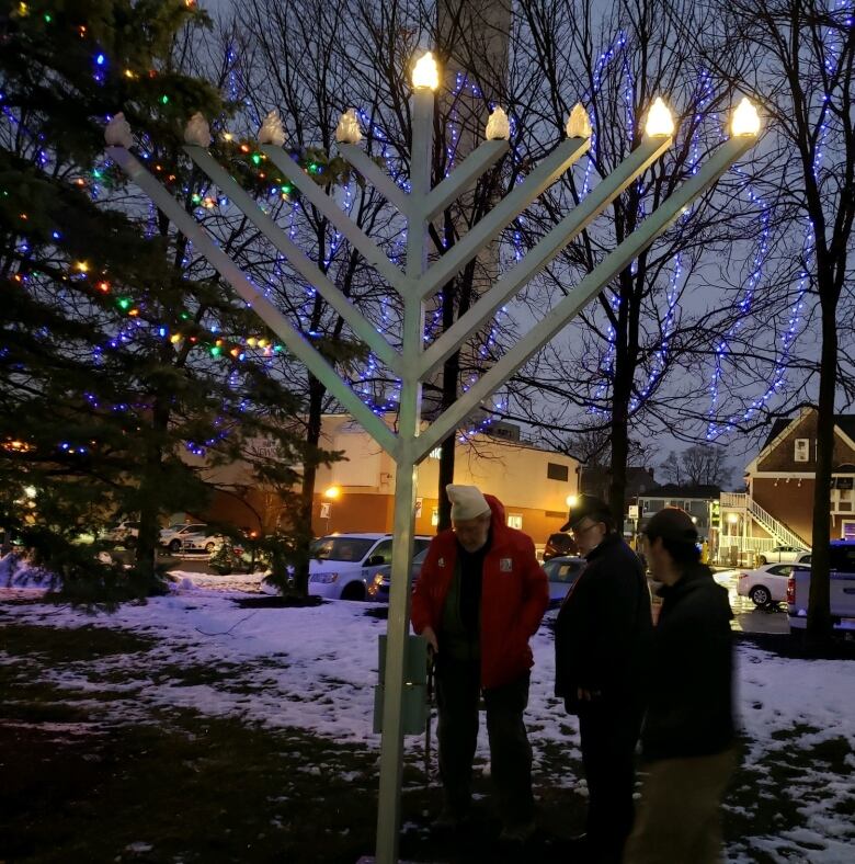 People gathered around large menorah at night time.