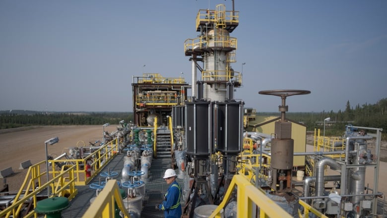 A worker stands on a steam-assisted gravity drainage pad at Cenovus' Sunrise oil facility northeast of Fort McMurray on Thursday, Aug. 31, 2023. Wildfires are bringing fresh scrutiny to Canada's fossil fuel dominance, its environmentally friendly image and the viability of becoming carbon neutral by 2050. (AP Photo/Victor R. Caivano)