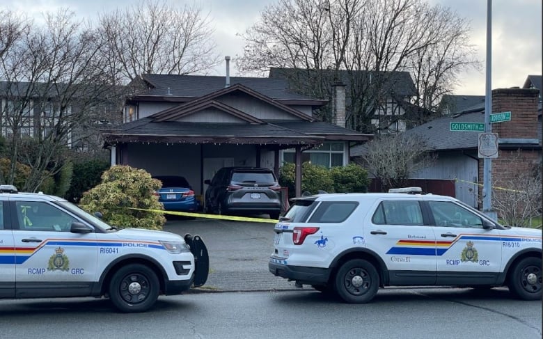 police cars parked on the street in front of a home behind police tape