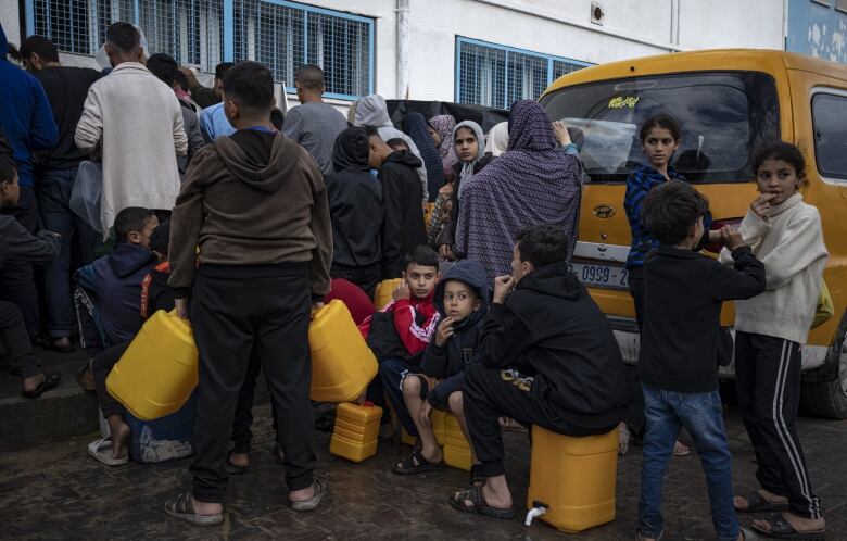 People with jugs line up for water.