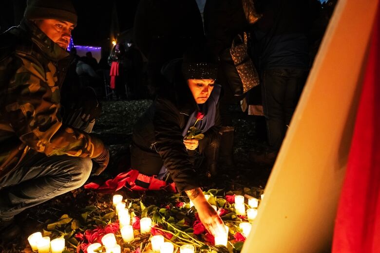 A woman stands in front of candles