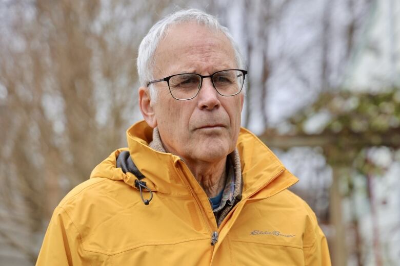 A man in a yellow rain jacket stands outside.