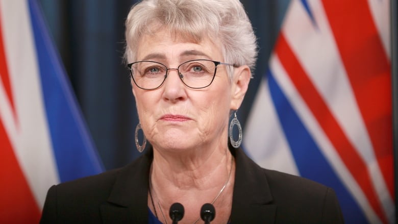 A close-up of a woman with short grey hair and glasses.