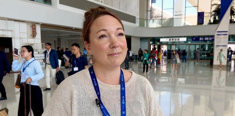 A woman is interviewed while people walk in the background through a conference centre.