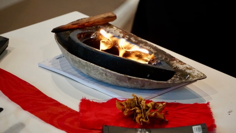 Small flames rise out of a small black dish, which sits on a white table.