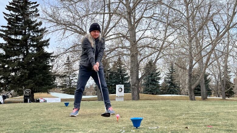 a woman prepared to hit a golf ball at a tee box