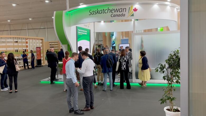 A group of people gather in a meeting in a green and white meeting space.