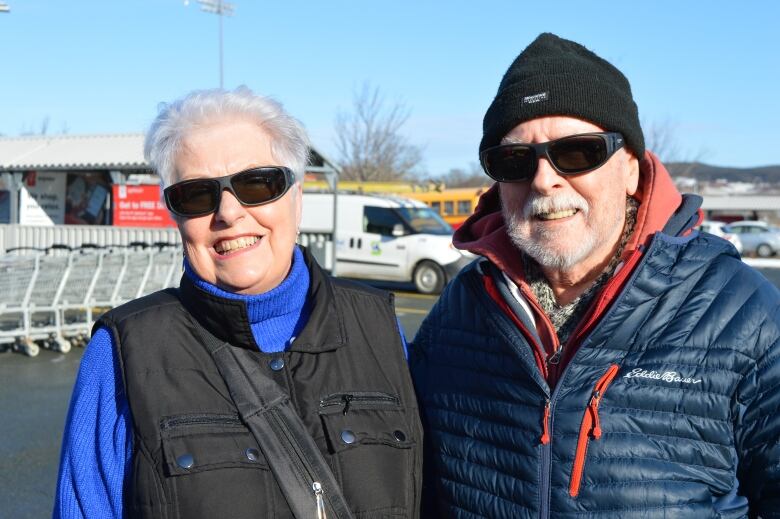 An older woman and her husband in a grocery store parking lot