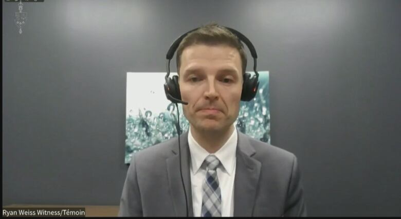 An insurance company executive appears on a video call, wearing a headset and suit.