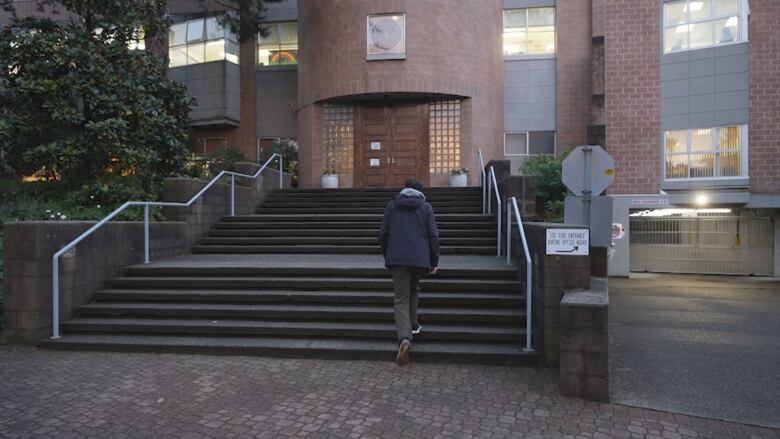 A man climbs up a stair leading to a synagogue building. 