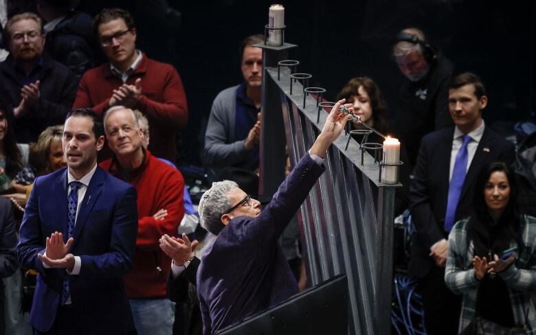 A man lights a menorah candle during a ceremony in Calgary.