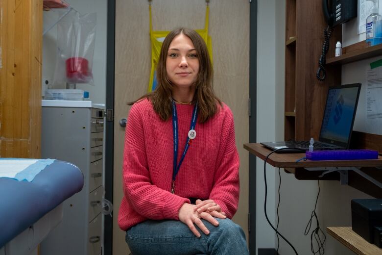 A person wearing a bright pink sweater sits in the middle of a room.