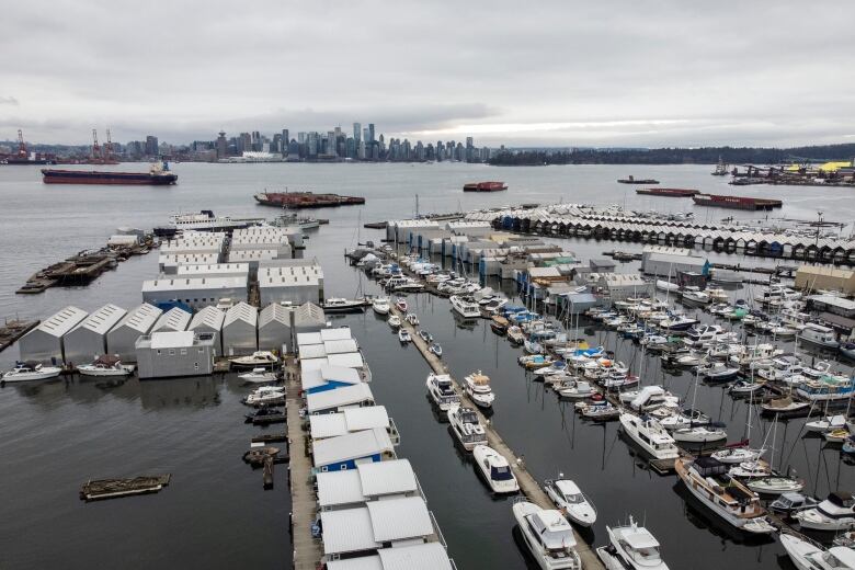 A photo taken by a drone shows the Mosquito Creek Marina, with Burrard Inlet and the Vancouver skyline in the background.