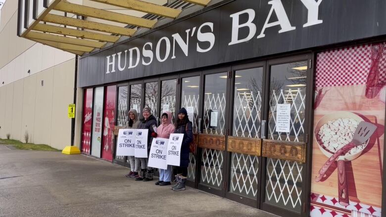 A small group of picketing workers stand outside a department store which has been closed.