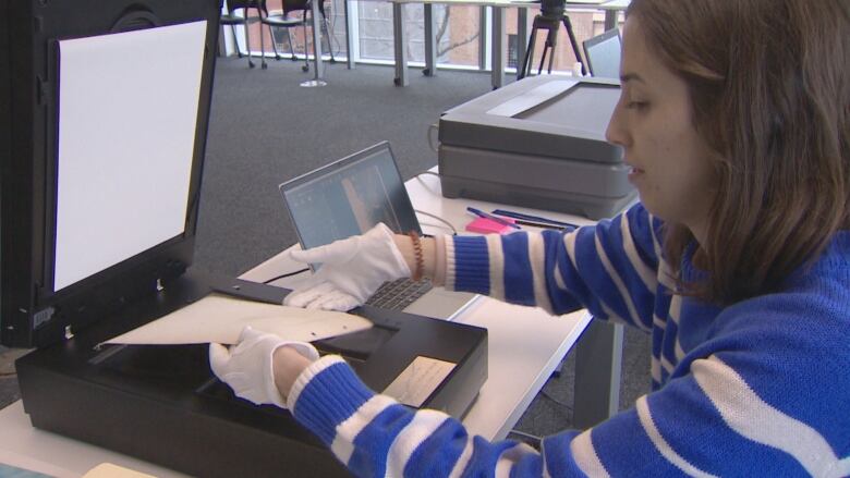 A woman in a blue and white striped sweater scans a document.