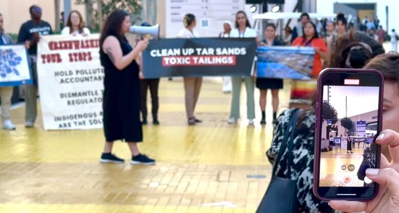 A person uses their phone to record a video of a protest.