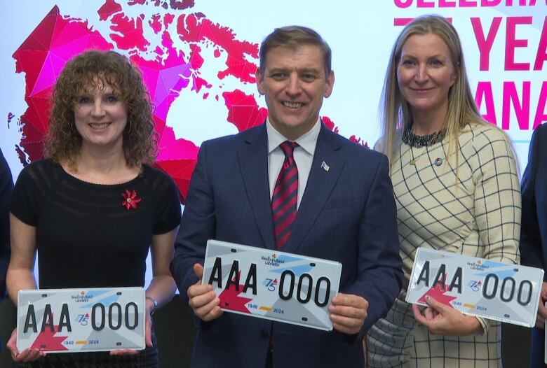 Two smiling women and a smiling man hold license plates. They have splashes of red, blue and grey, and feature a 75 logo in between the letters and numbers.