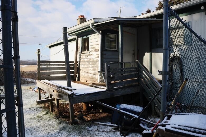 A run-down mobile home with a chain-link fence. 