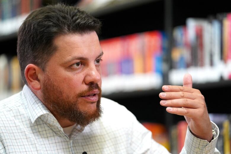 A bearded man speaks and gestures. 