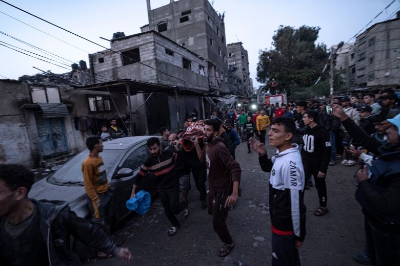 Men carry a body wrapped in a white sheet from a site of an Israeli airstrike.