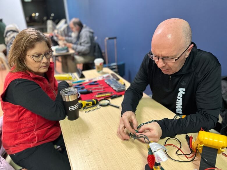 woman looks on as man fixes lights