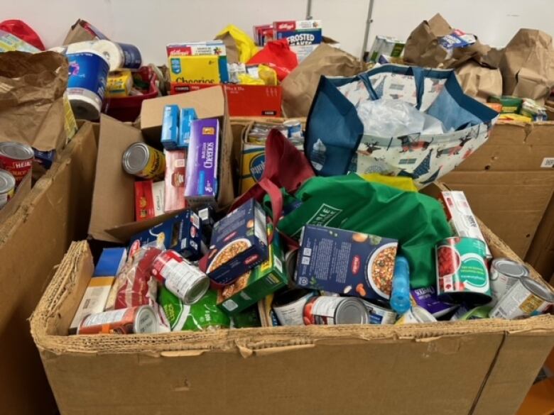 Thee brown boxes stuffed full with foods like canned soups, pastas and cereals. 