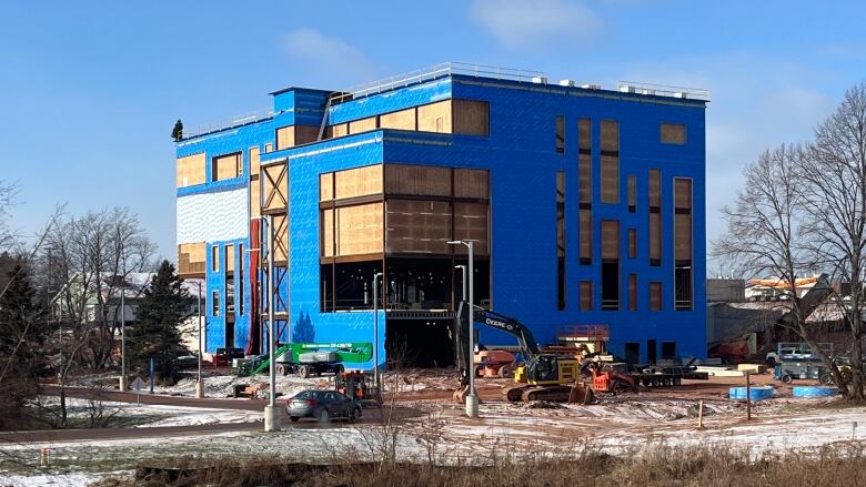 Large building under construction surrounded by heavy machinery.