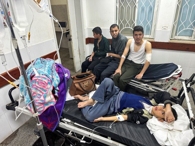 A boy lies on a bed as he receives treatment in a hospital.