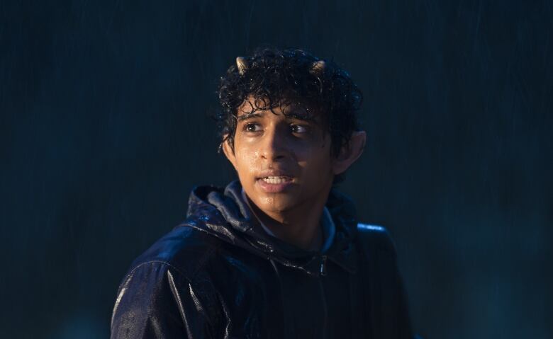 A young teen stands in the rain.