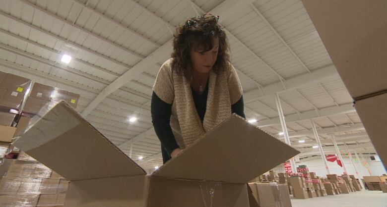 A woman looks inside a box in a warehouse.