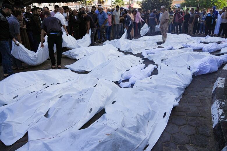 Palestinians mourn relatives killed in the Israeli bombardment of the Gaza Strip in front of the morgue in Deir al Balah, Sunday, Nov. 6, 2023.