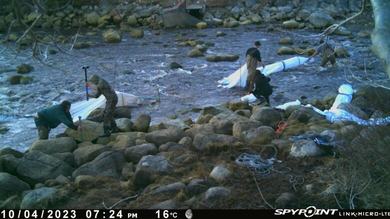 People can be seen setting up nets to fish for baby eels on a river in Halifax County, N.S., in 2023. The image was captured on a trail cam set up by a licence holder to monitor elver fishing activity in 2023.