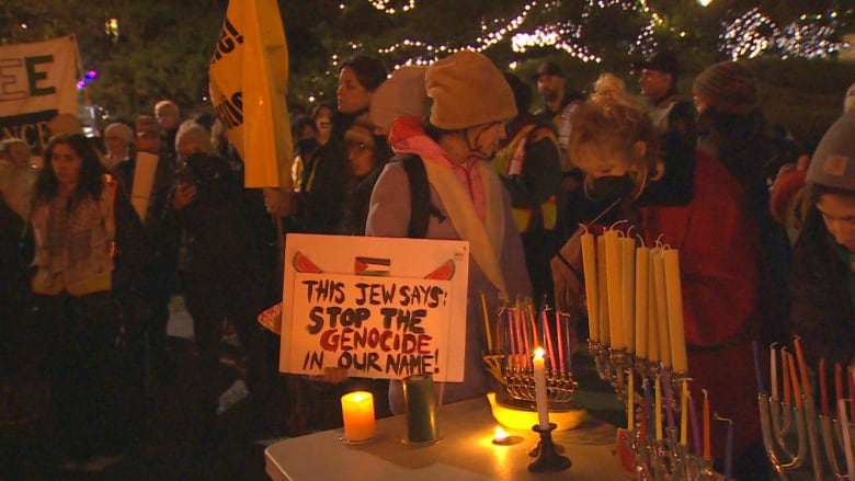 Menorah are lit on a table, with a sign saying 