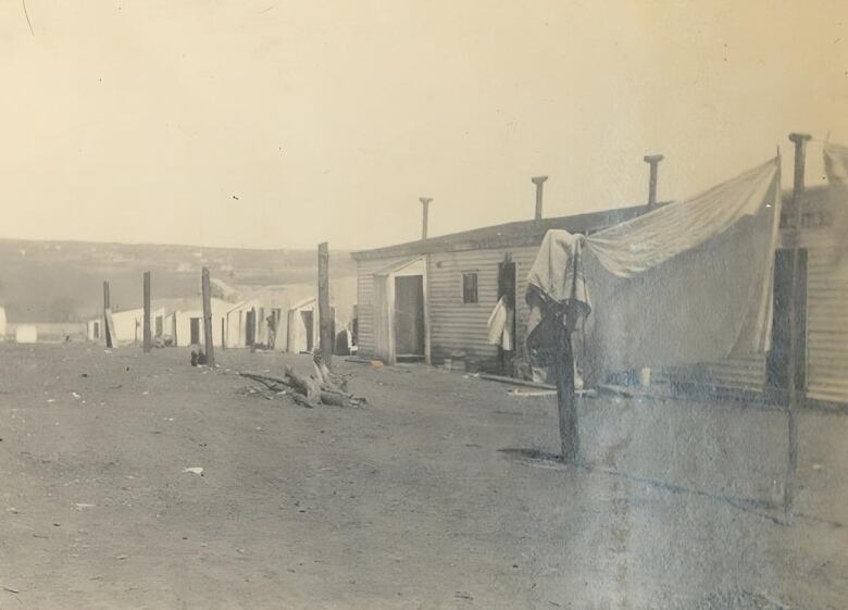 A laundry line blows in front of a line of temporary structures. 