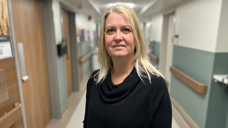 A woman stands facing the camera in a hospital hallway.