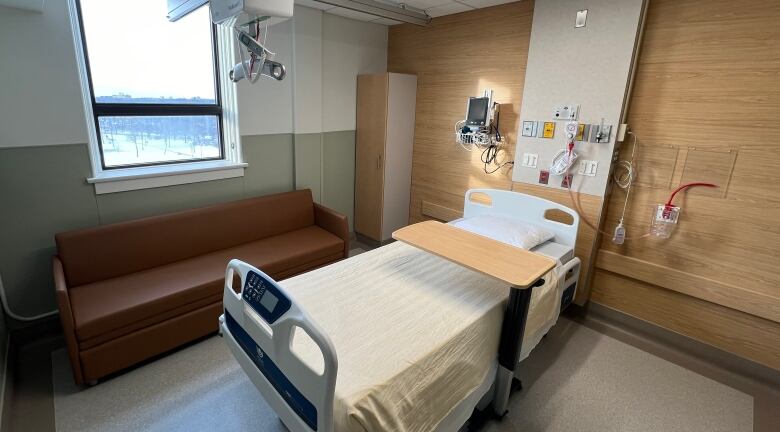 An empty bed is shown in a hospital room.