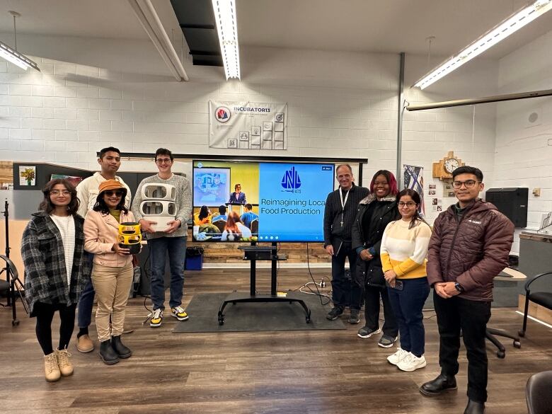 A group stands in front of a large screen.